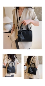 Detail view of black leather tote bag with small triangle coin purse and shoulder strap