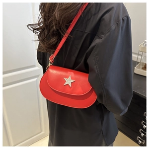 Detail of red star-embellished saddle bag worn by model over a black shirt