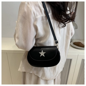 Detail of a black faux leather saddle bag with a sparkling rhinestone star on a model