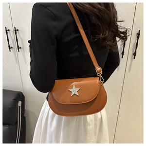 Brown half-moon crossbody bag with star rhinestone detail shown on model back shoulder