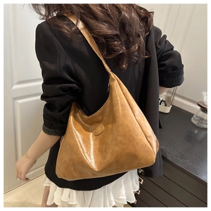 Close-up of caramel soft leather tote bag with round logo patch and retro finish
