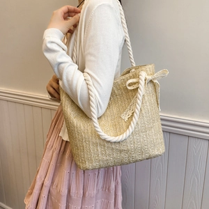 Beige woven straw tote bag with rope straps and white lace bow decoration for women