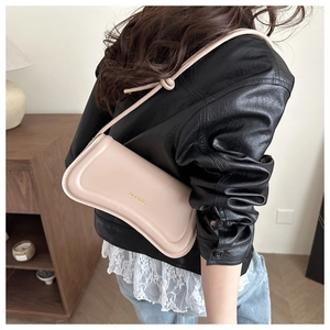 Detail of light beige baguette bag with decorative rope strap shown on model's shoulder
