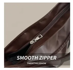 Détail de la fermeture éclair en argent sur le sac à dos en cuir marron foncé et couture