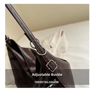 Détail de la boucle argentée réglable et de la sangle à double anneau d'un sac marron