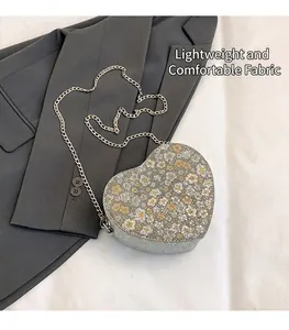 Detail view of heart-shaped glitter bag with floral pattern and silver chain strap