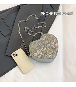 Detailed size comparison of the heart-shaped floral chain bag next to a smartphone