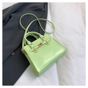 Detail of mint green textured faux leather handbag with elegant gold hardware turn-lock