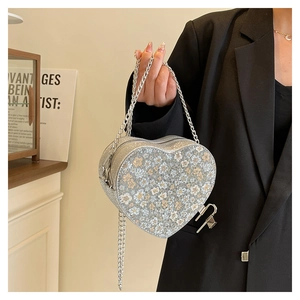 Detail of silver heart-shaped sequin bag with metal chain strap and decorative padlock