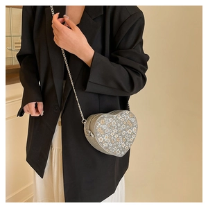 Detail view of heart-shaped crossbody bag with silver sequins and floral patterns
