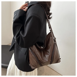 Détail du sac à dos en cuir marron foncé avec fermeture éclair et bandoulière réglable