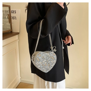 Close-up of heart-shaped silver sequin crossbody bag with floral pattern and metal chain