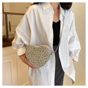 Detail of heart-shaped sequin crossbody bag with floral patterns and silver chain strap