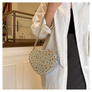 Detail shot of heart-shaped sequin evening bag with silver and yellow crystal floral patterns