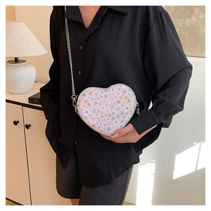 Detail of heart-shaped sequin crossbody bag featuring colorful floral pattern and metal chain