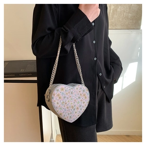 Detail of silver heart-shaped bag with purple floral sequins and metallic chain strap