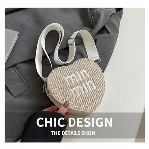 Close-up of heart-shaped straw crossbody bag with min min embroidery and wide strap