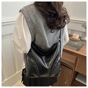 Détail d'un sac hobo en cuir PU noir avec fermetures éclair décoratives et bandoulière