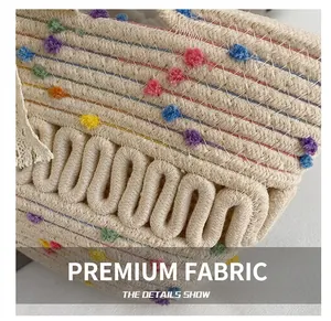 Close-up of woven straw tote bag with colorful pompoms and wavy texture details