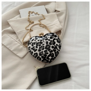 Detail view of heart-shaped leopard print clutch bag next to a smartphone for size reference