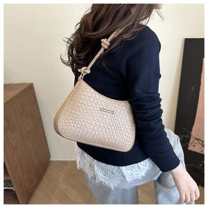 Détail du sac beige avec texture tressée et bandoulière à nœud au style minimaliste