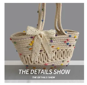 Close-up of handmade straw bag with colorful pom-poms, lace bow and wave weave texture