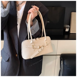 Macro detail of creamy white textured leather baguette bag with elegant golden metal buckle