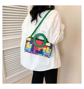 Detalle de bolso geométrico colorido con asa circular verde de diseño exclusivo