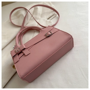 Close-up of pink crossbody bag with decorative bow and fine stitching details