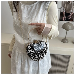 Detail of leopard print heart-shaped crossbody bag with gold chain and metal handle