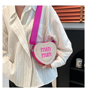 Detail of heart-shaped woven crossbody bag with pink leather trim and adjustable strap