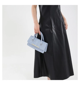 Close-up of light blue woven texture handbag with luxury gold hardware details