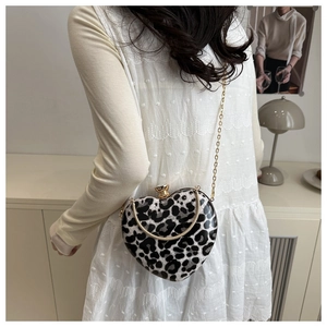 Detail view of heart-shaped crossbody bag with leopard print and gold chain strap