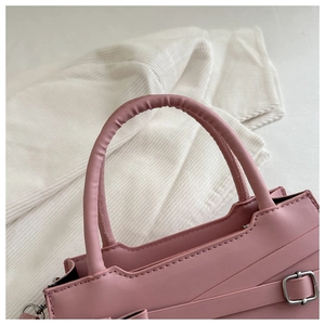 Détail du sac à main en similicuir rose avec boucle en métal et texture de lanière