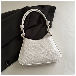 Detail shot of a beige woven hobo bag with thick shoulder strap on a black blazer