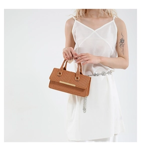 Close-up of woven brown leather handbag with minimalist gold metal decorative bar