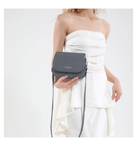 Close-up of grey textured saddle bag with Fashion Trend logo and thin shoulder strap