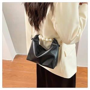 Detail of black PU crossbody bag featuring oversized pearl handle and gold chain strap