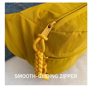 Detail showing smooth metal zipper with woven ginger yellow puller on crossbody bag