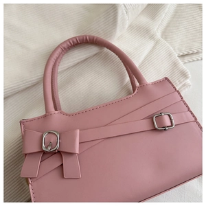 Gros plan sur le sac à main carré rose montrant la texture cuir et la boucle argentée