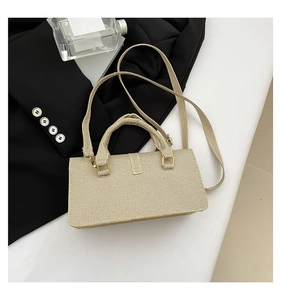 Detail of beige textured fabric handbag with gold hardware and reinforced top handle