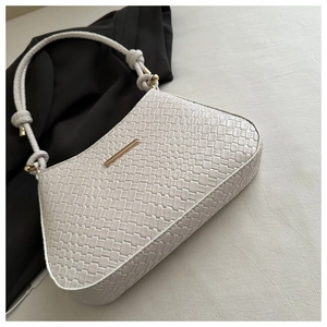 Dettaglio della trama intrecciata su una borsa a tracolla bianca con accenti dorati