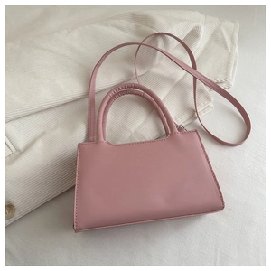 Pink matte leather trapezoidal handbag featuring dual cylindrical handles and slim strap