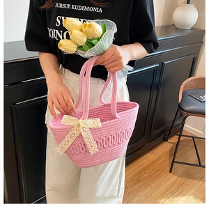 Detailed close-up of pink woven beach tote with delicate white lace bow and sturdy handles