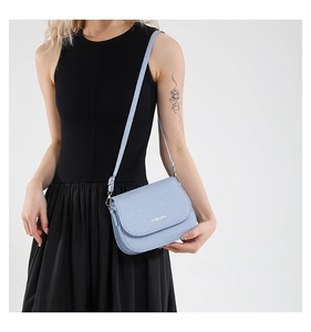 Close-up of light blue quilted crossbody bag with gold Fashion Trend logo and strap