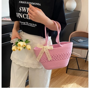Close-up of pink woven bucket bag with elegant white lace bow detail and soft texture