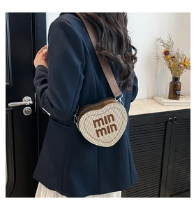 Fashionable heart-shaped crossbody bag featuring beige woven fabric and leather straps