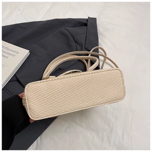 Detailed base and woven texture of a beige pillow shoulder bag with slim strap