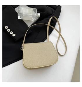 Close-up of beige saddle bag with diagonal weave texture and wide fabric strap