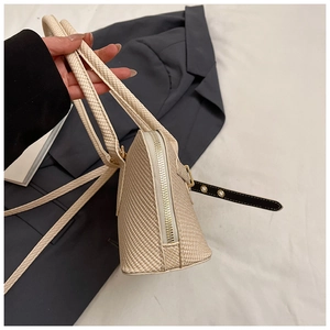 Detail showing beige woven texture and golden zipper of this stylish shoulder bag